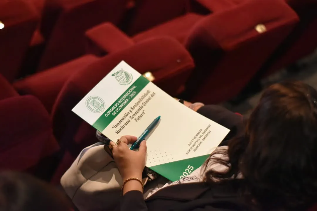Una asistente con el programa del congreso y una lapicera en la mano, en la platea del salón de convenciones