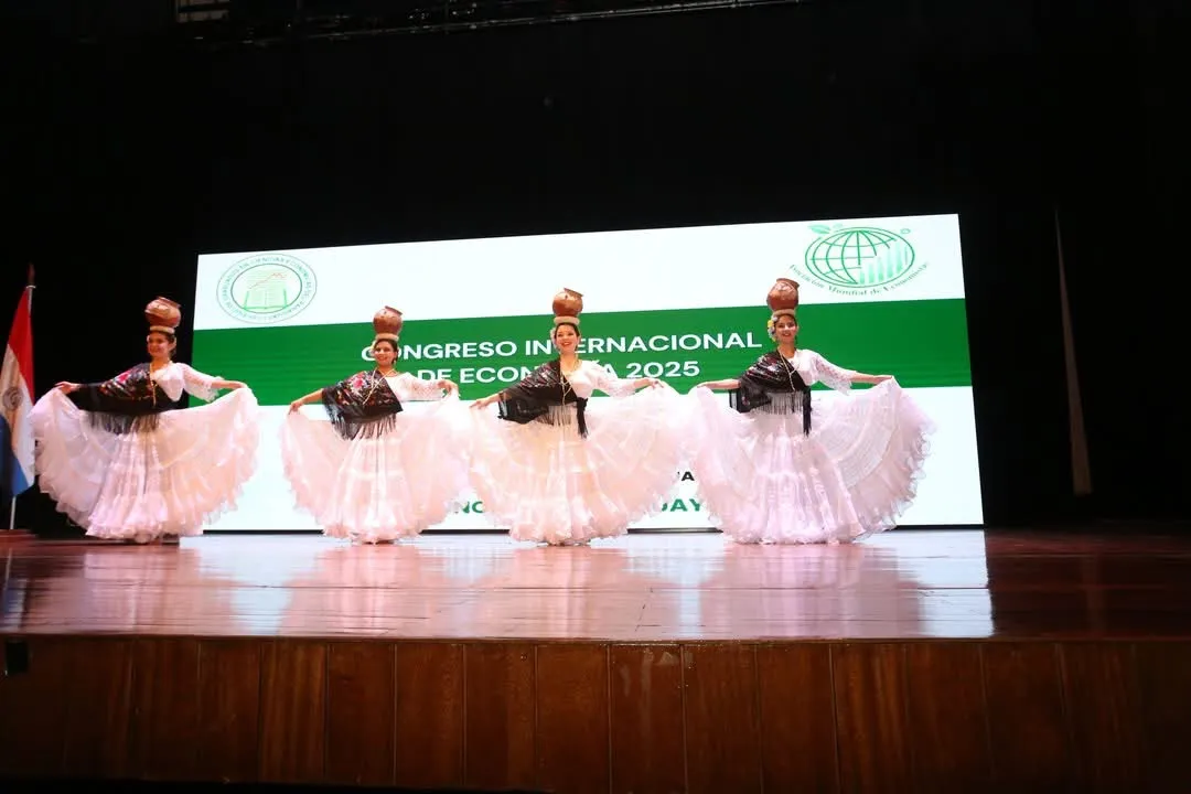 Cuatro bailarinas de danza paraguaya con cántaros en la cabeza, sobre el escenario del congreso