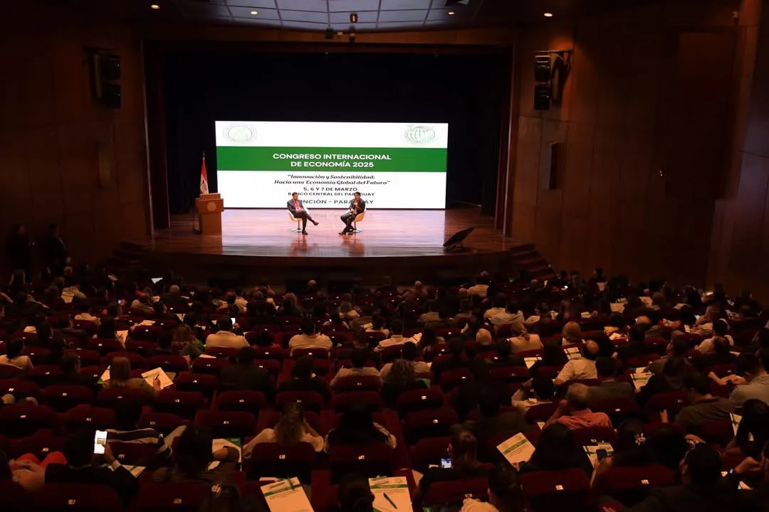 Vista general del salón de convenciones lleno, con la pantalla del congreso al fondo del escenario